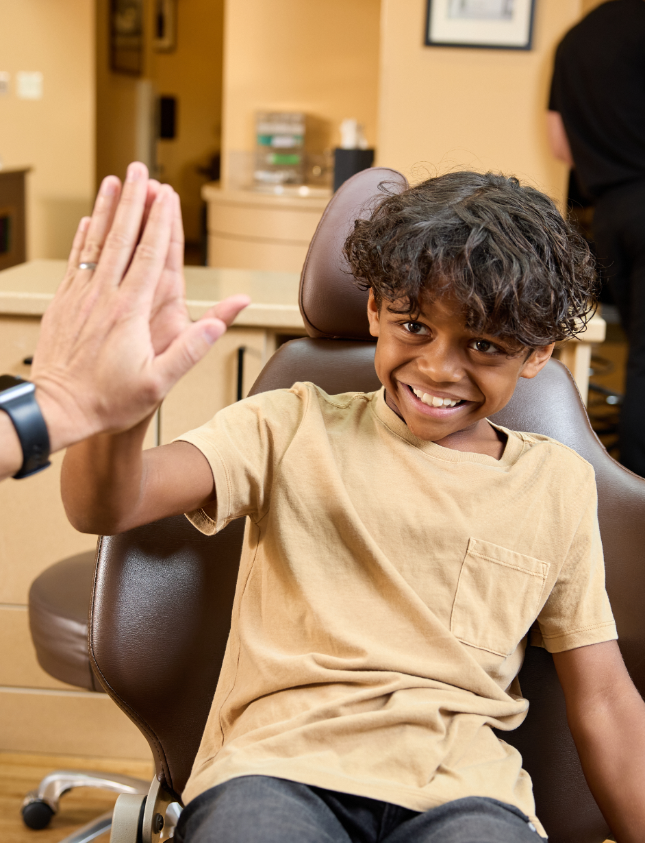 boy in dental chair giving a high five