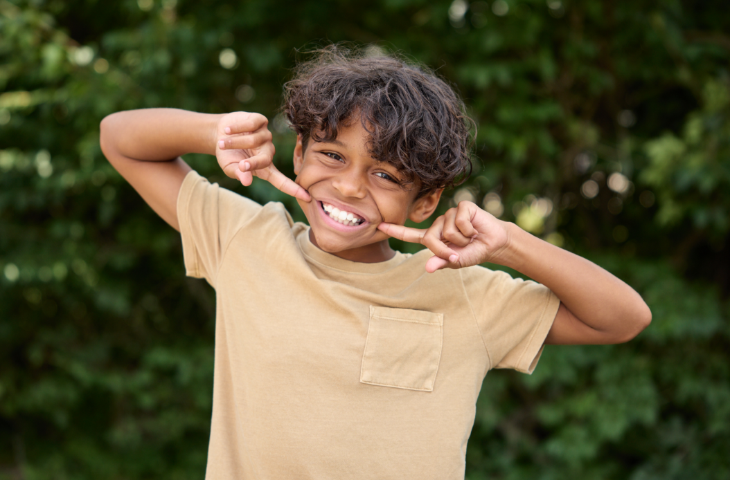 child smiling big and pointing at his mouth
