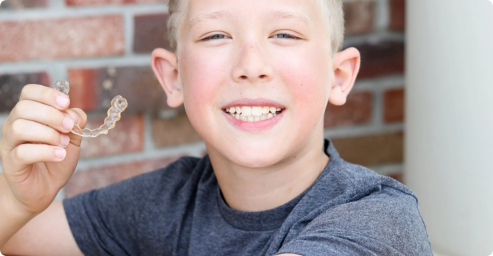 boy smiling holding invisalign