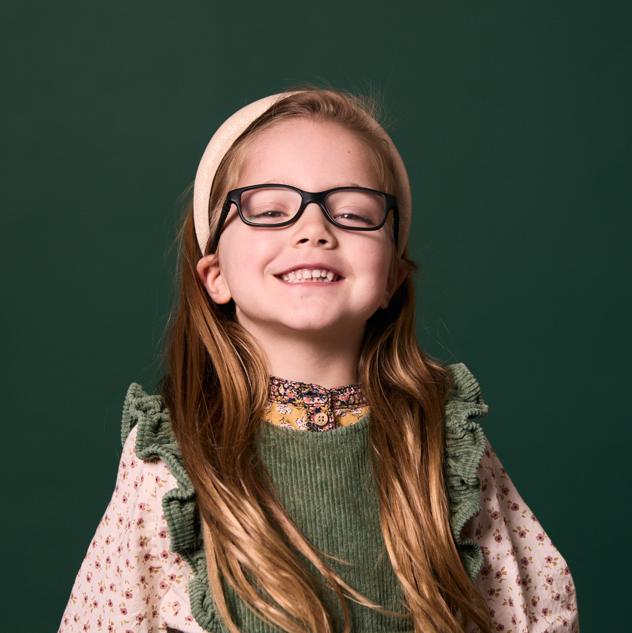Little girl with black glasses smiling at Rochford Orthodontics.