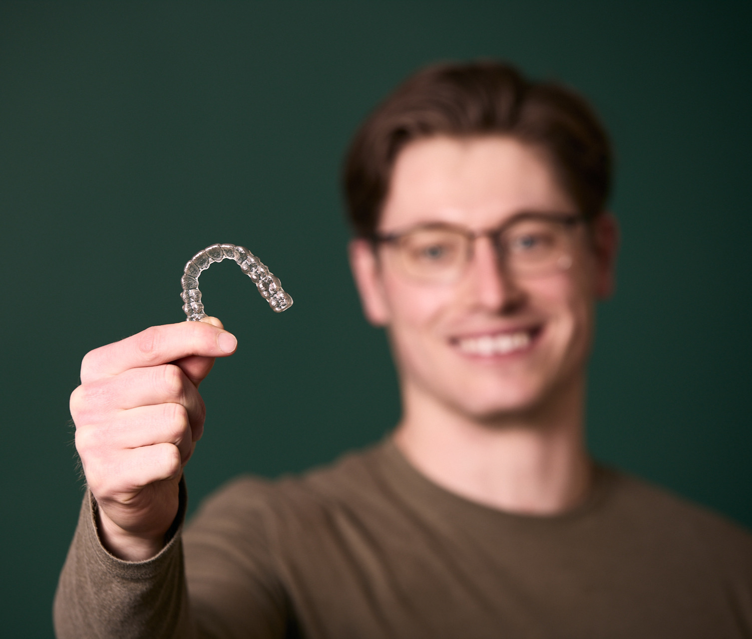 Man smiling holding Invisalign trays at Rochford Orthodontics.