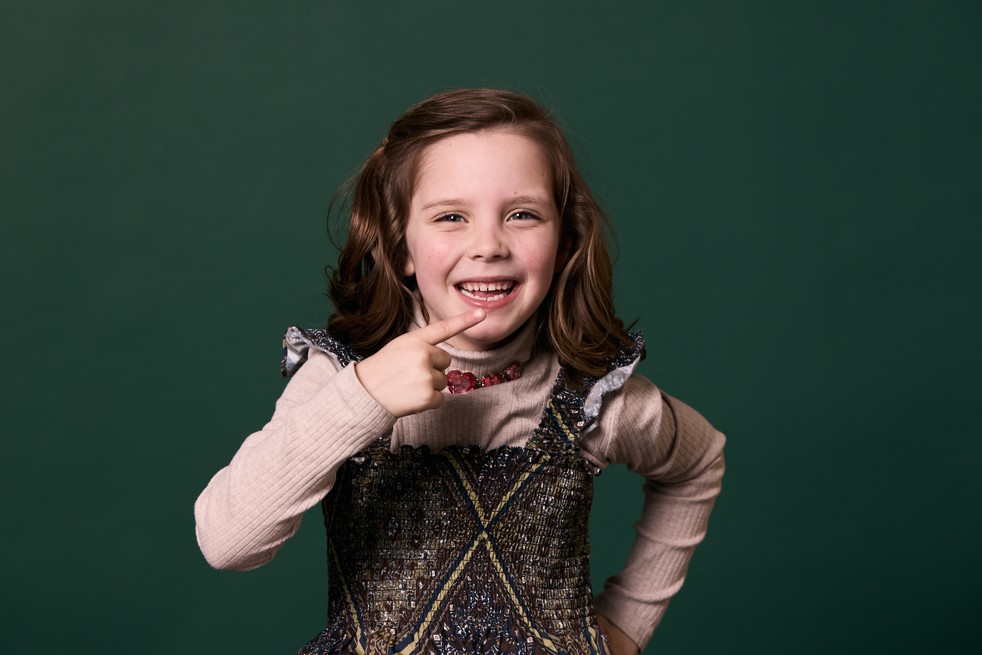 Little girl pointing to her mouth and smiling at Rochford Orthodontics.