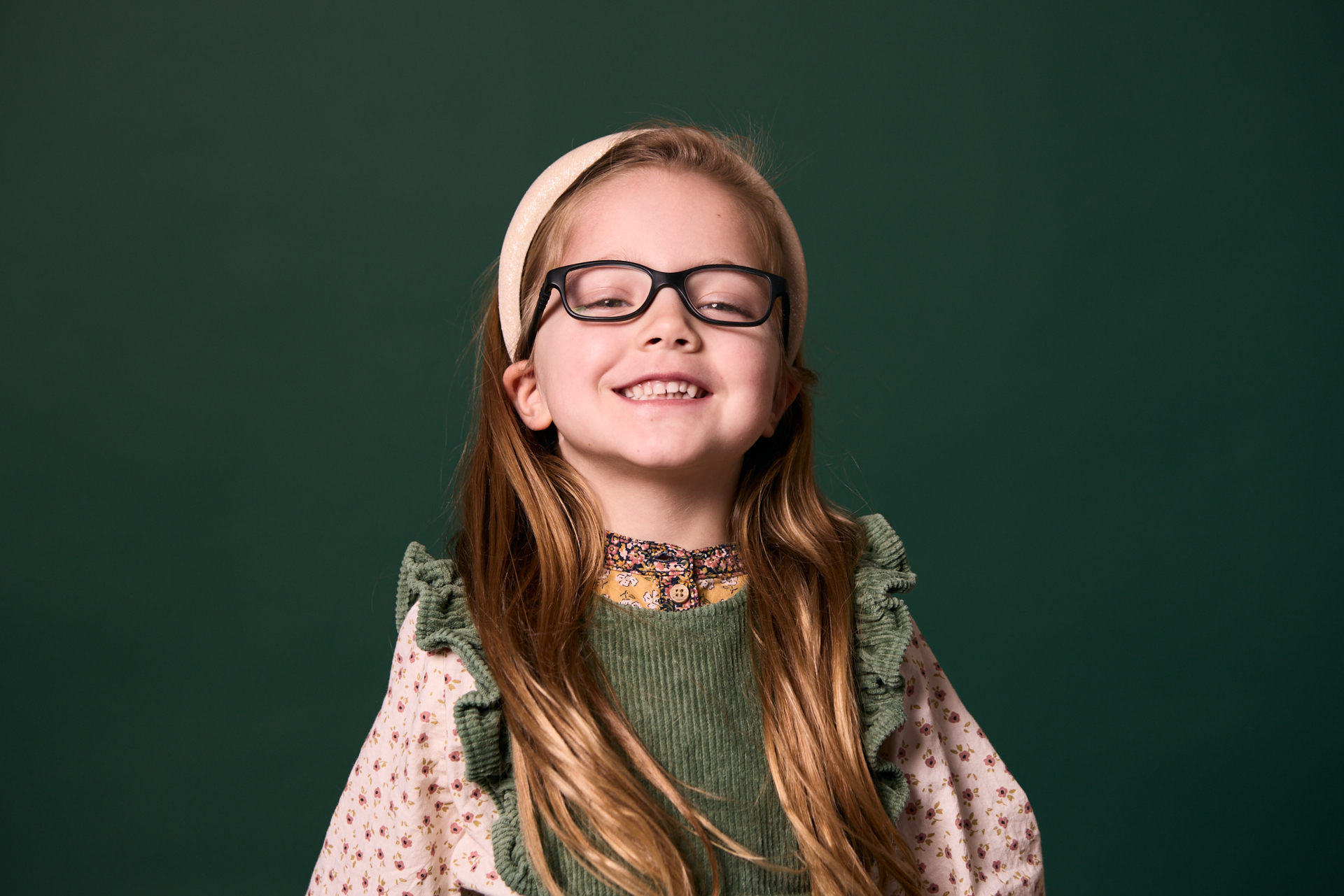 Little girl with black glasses smiling at Rochford Orthodontics.