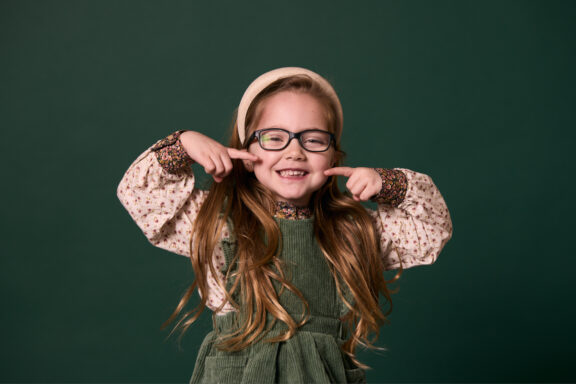 Little girl pointing to her mouth and smiling at Rochford Orthodontics.