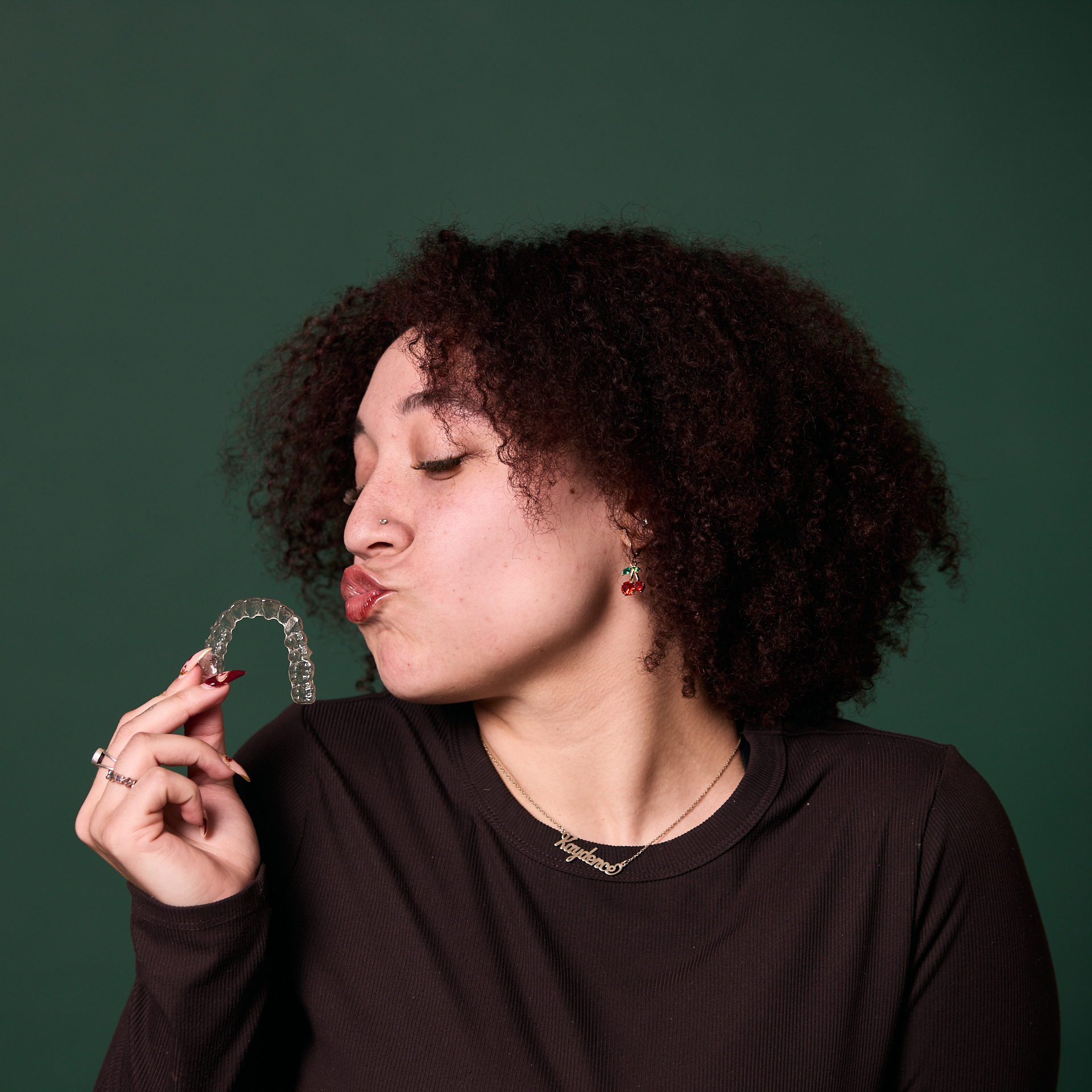 Woman making a kissy face at Invisalign trays at Rochford Orthodontics.