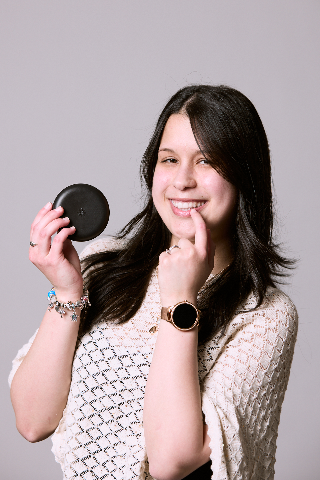Woman pointing to her tooth holding an Invisalign case at Rochford Orthodontics.
