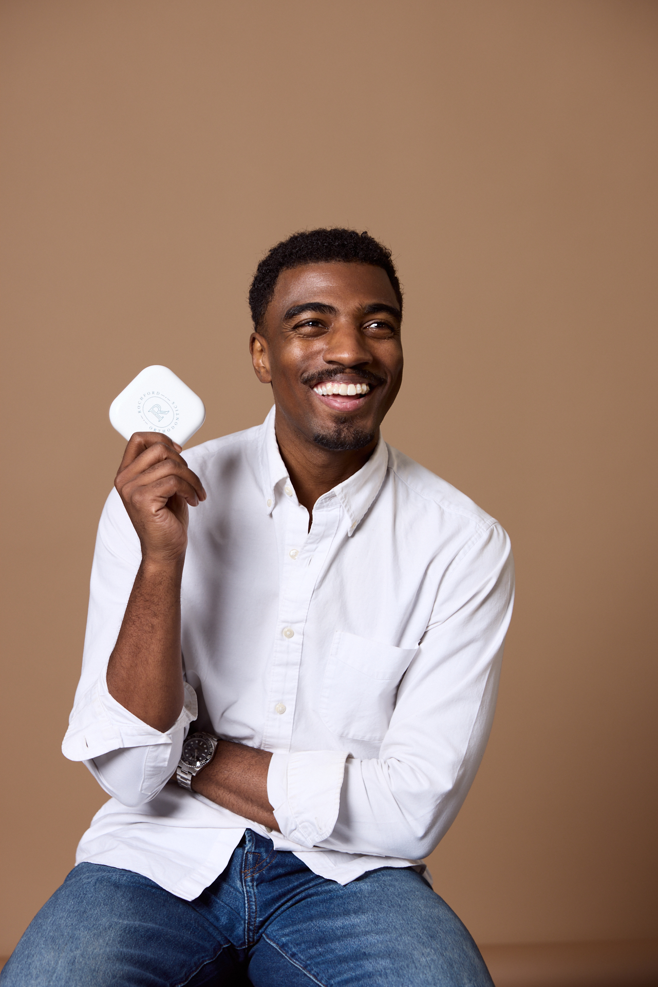 Man smiling and holding a Rochford Orthodontics retainer case.